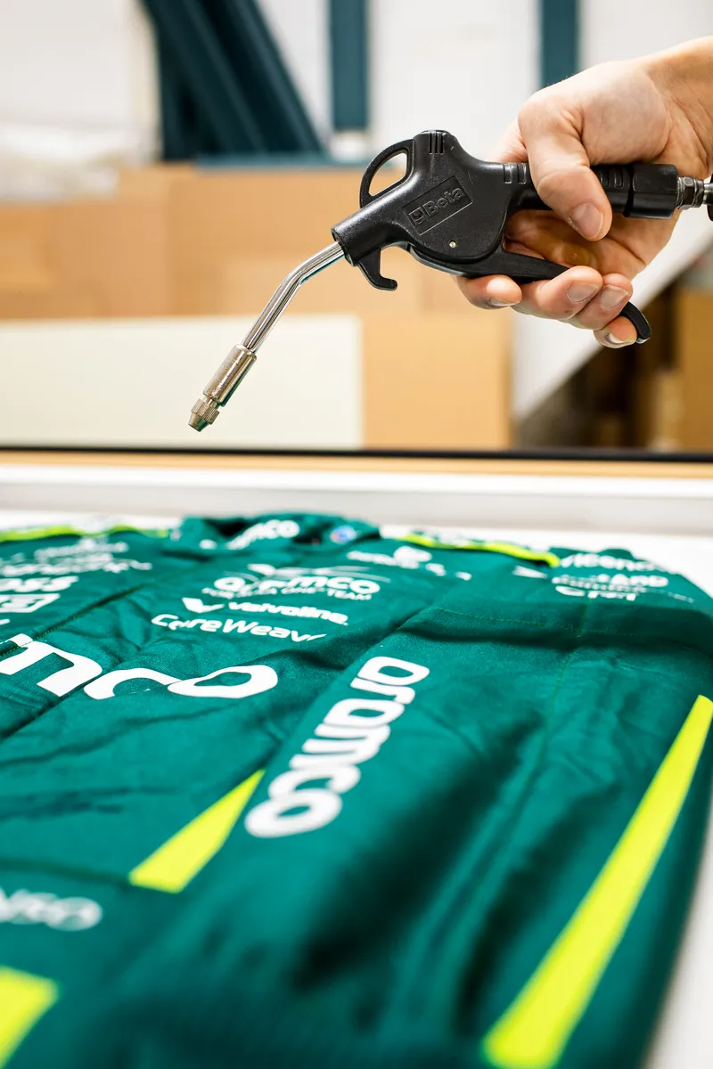 Blowing the dust off a Fernando Alonso race suit in our workshop before framing